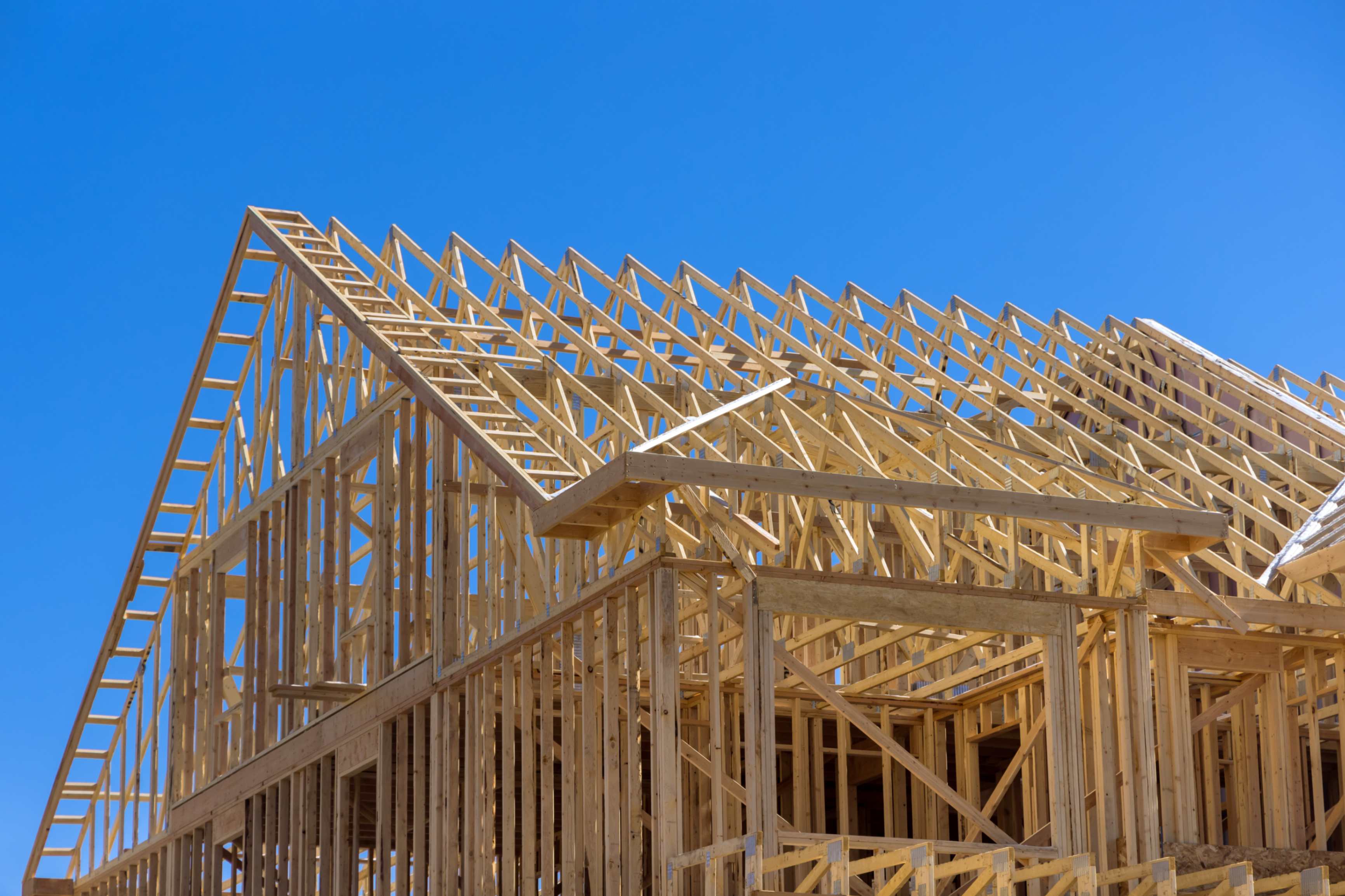 Wooden house frame under clear blue sky.