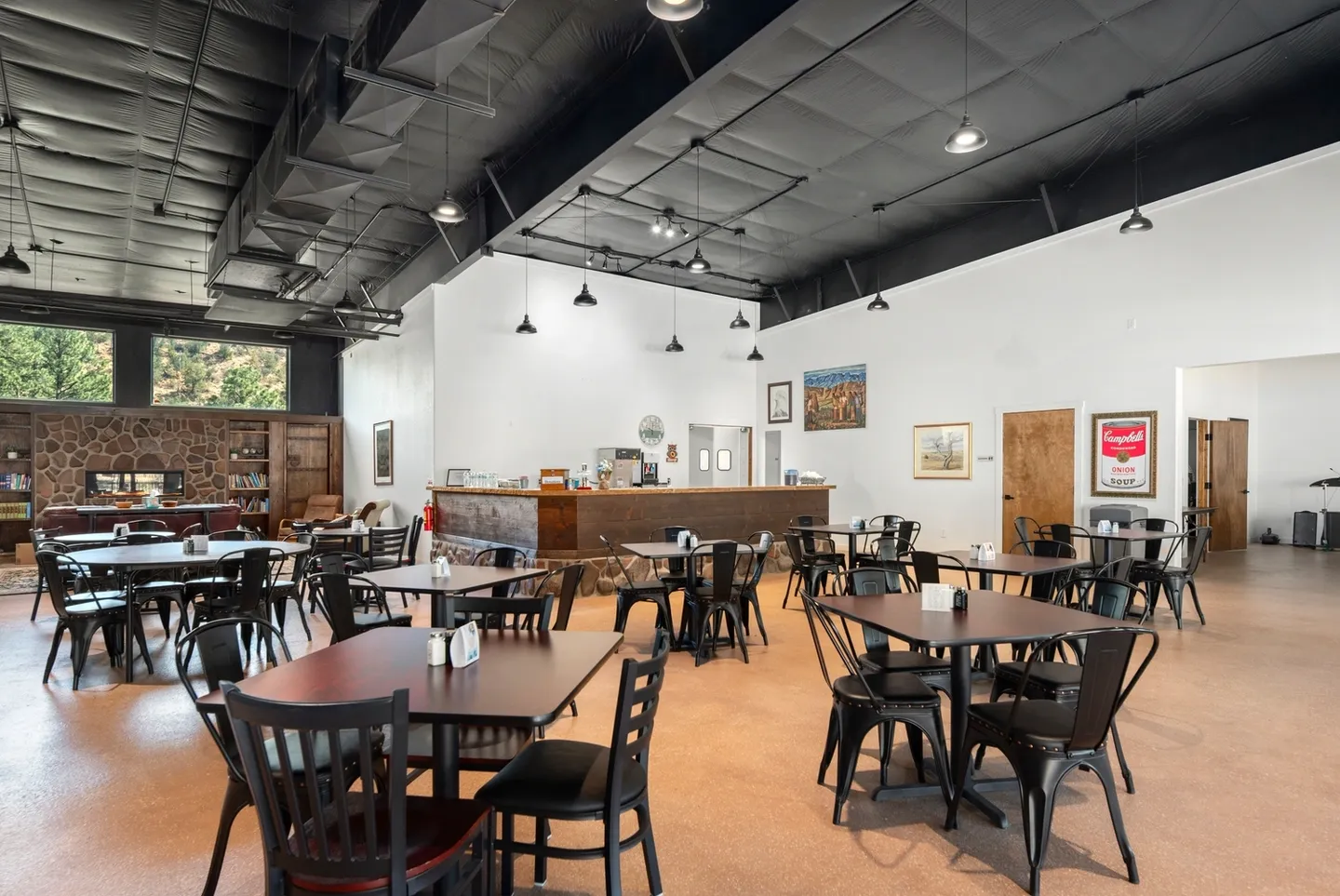 Spacious, modern dining area with wooden tables and black chairs.