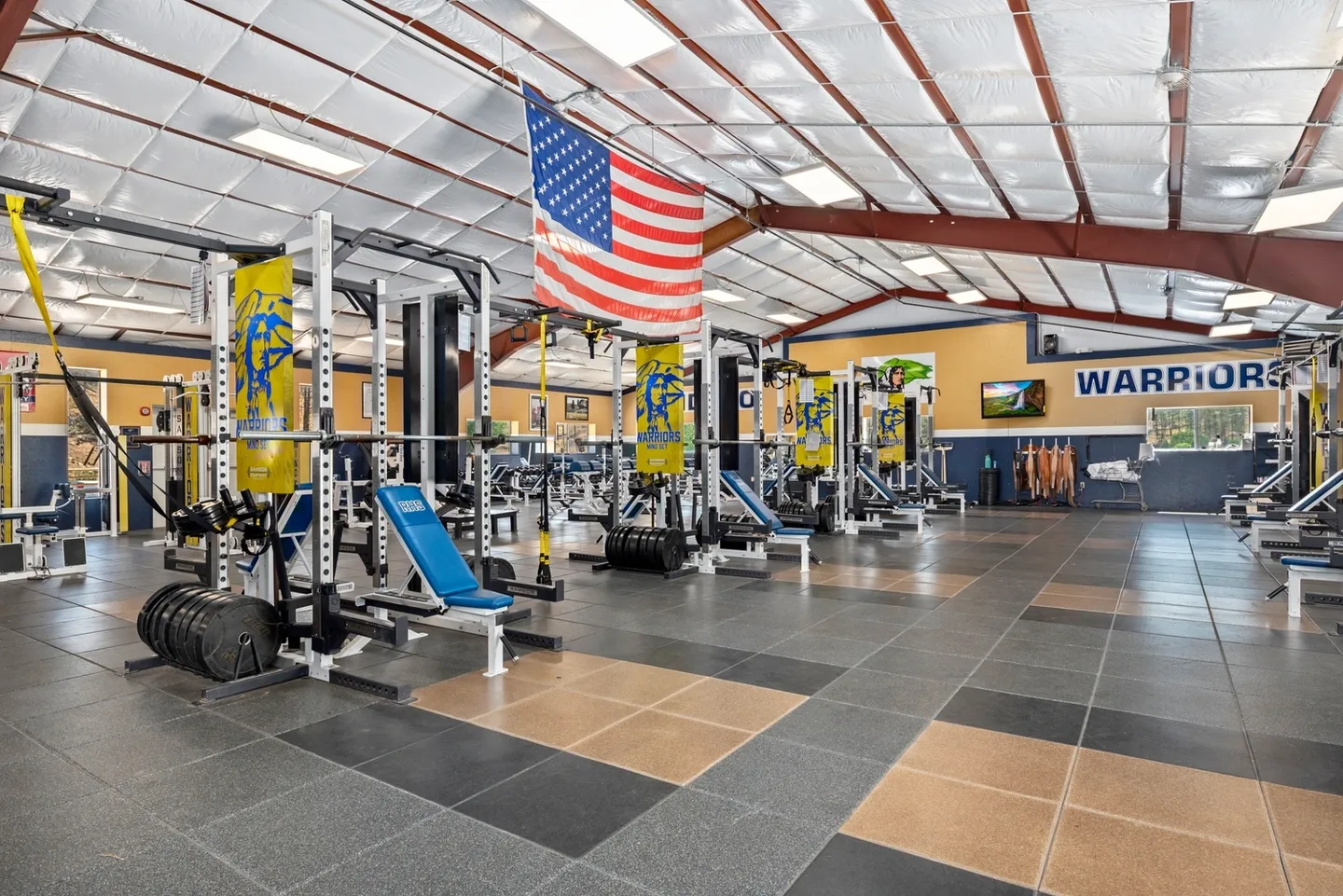 Spacious gym with modern equipment and an American flag overhead.
