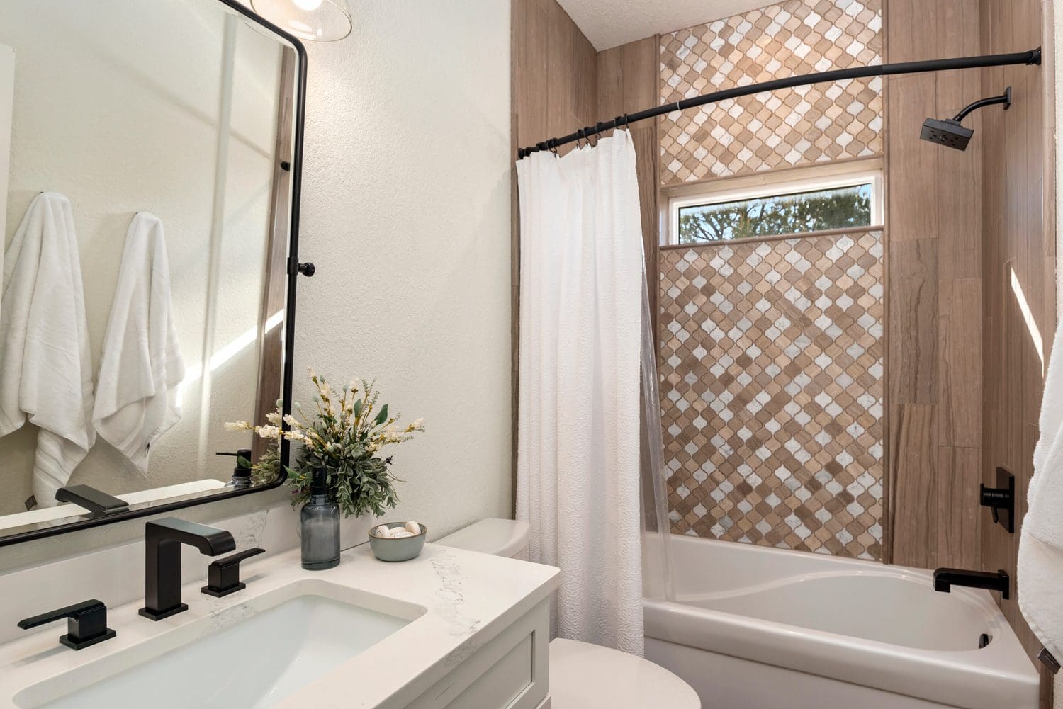 Modern bathroom with white and beige tones and a patterned accent wall.