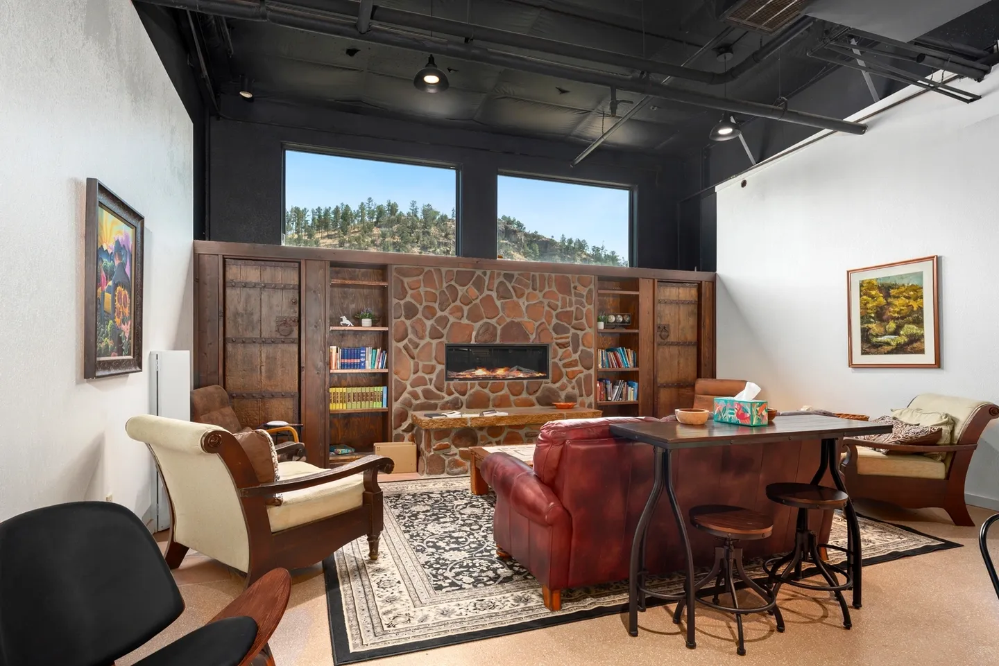Cozy living room with leather sofa and brick fireplace under large windows.