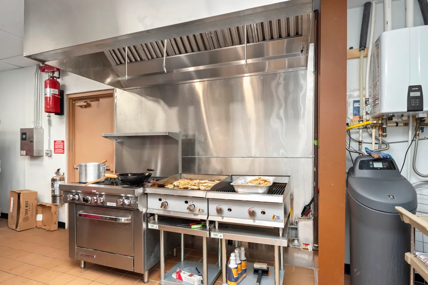 Commercial kitchen with stainless steel appliances and cooking stations.