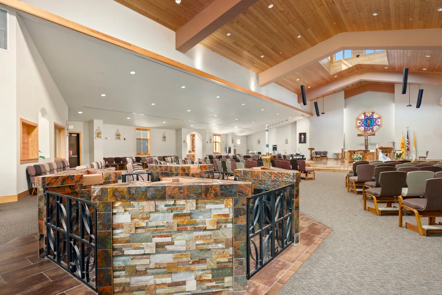 Spacious church interior with wooden ceiling and stone altar.