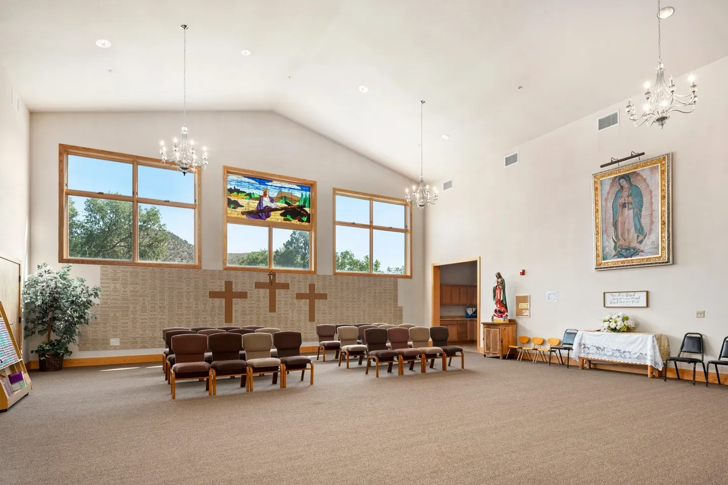 A bright, spacious church interior with wooden pews and three crosses.
