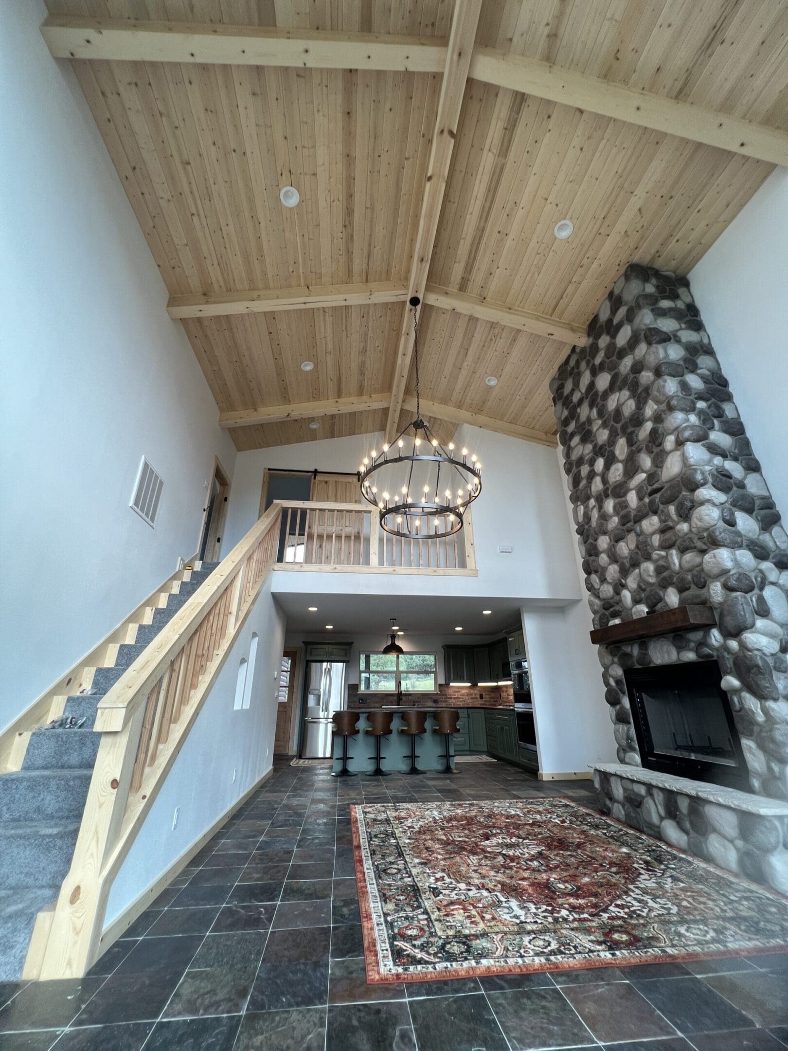 Spacious living room with high wooden ceiling and stone fireplace.
