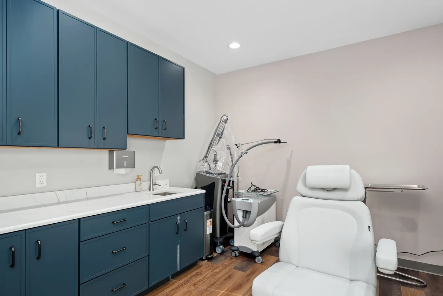 A modern clinic room with treatment chair and medical equipment.