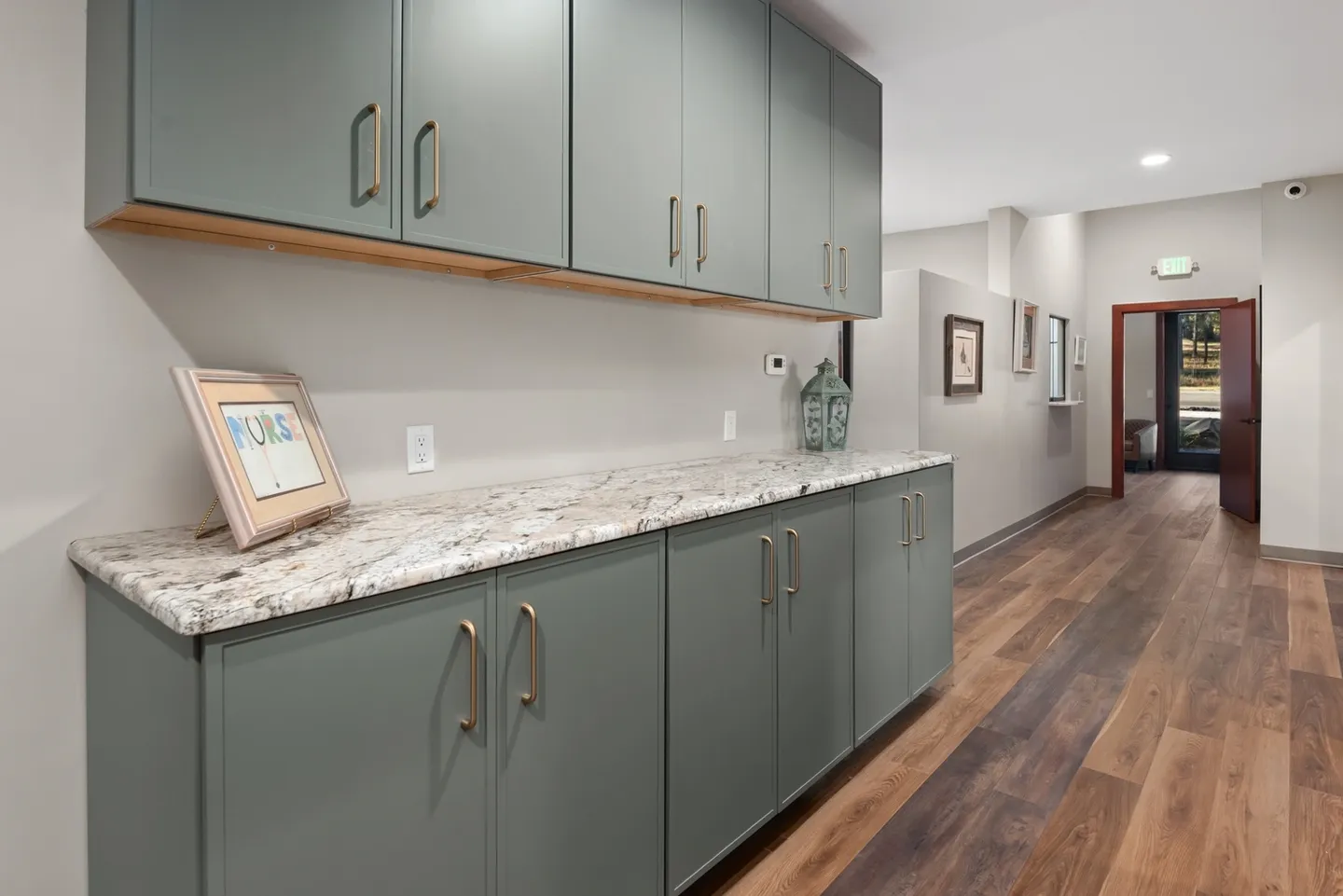 Modern kitchen with gray cabinets and wooden flooring.