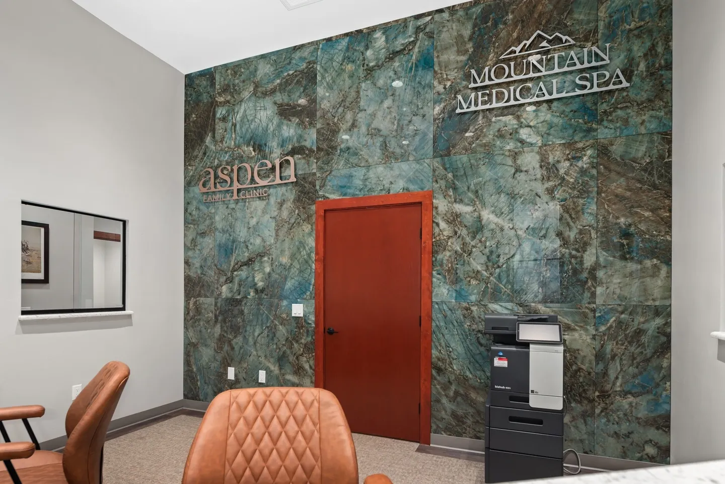 Modern office corner with textured wall and closed red door.