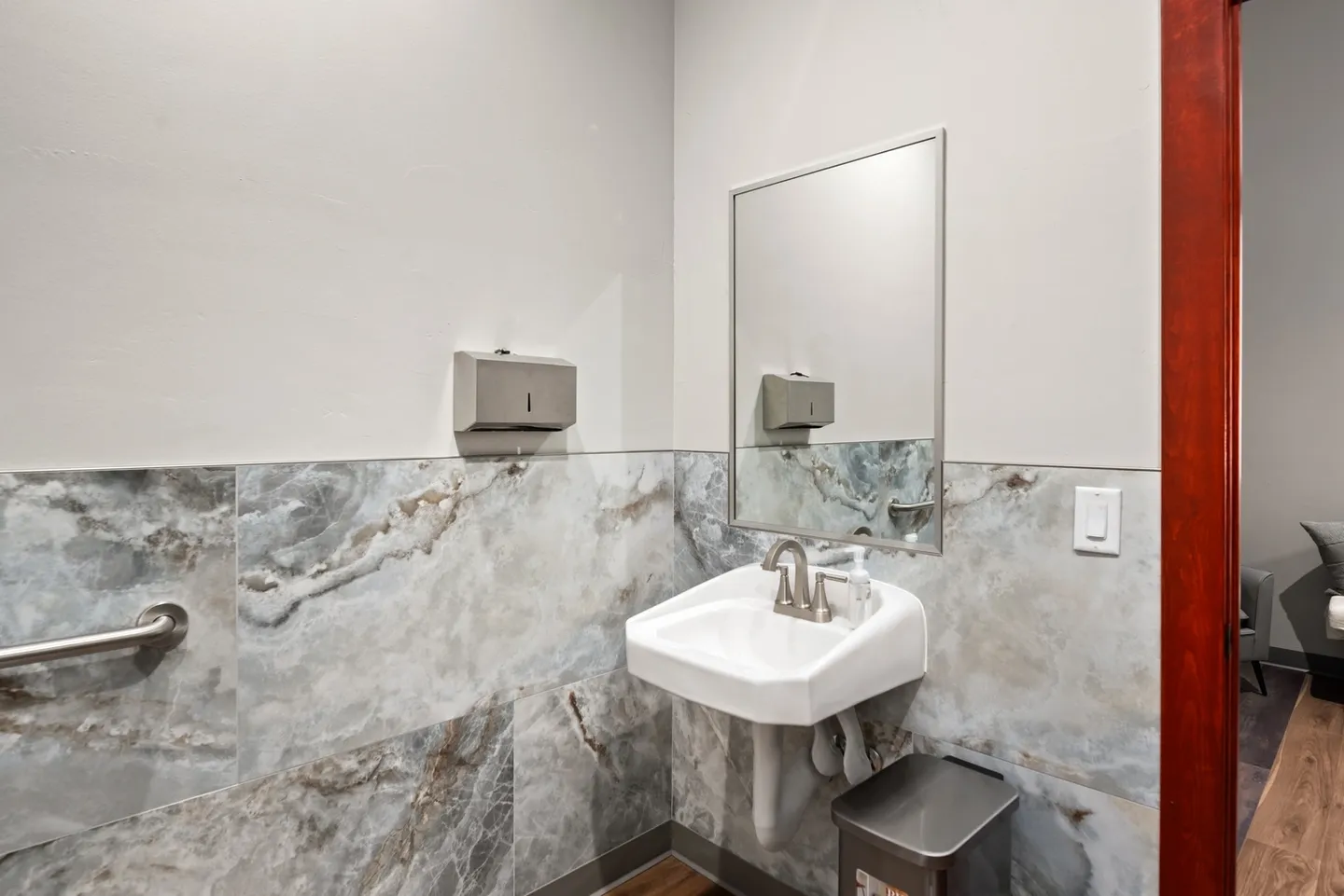 Minimalist bathroom with marble walls and a pedestal sink.