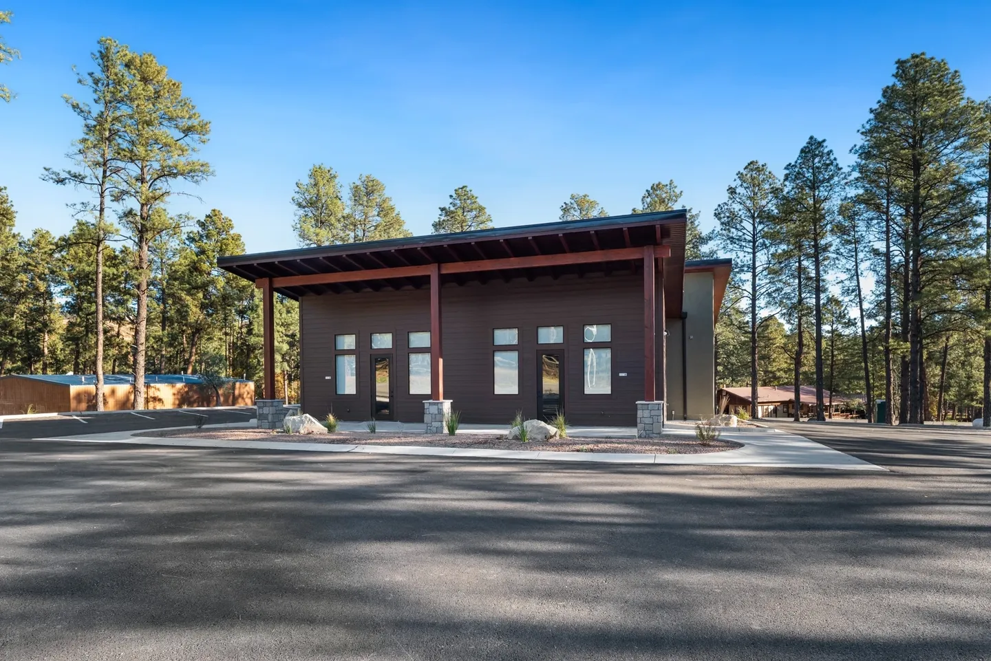 Modern building with large windows surrounded by trees under a clear sky.