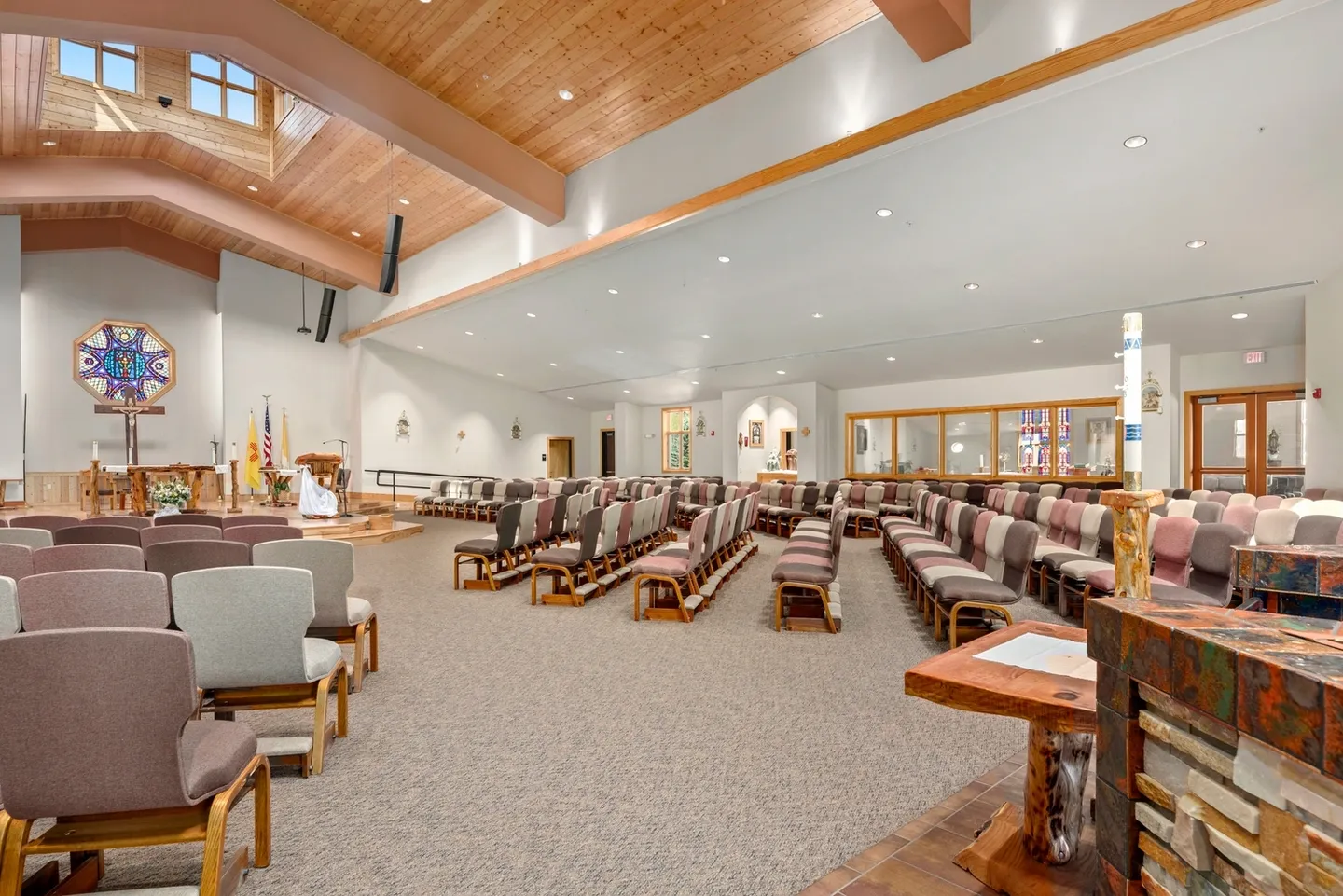 Spacious church interior with wooden ceiling and rows of pews.