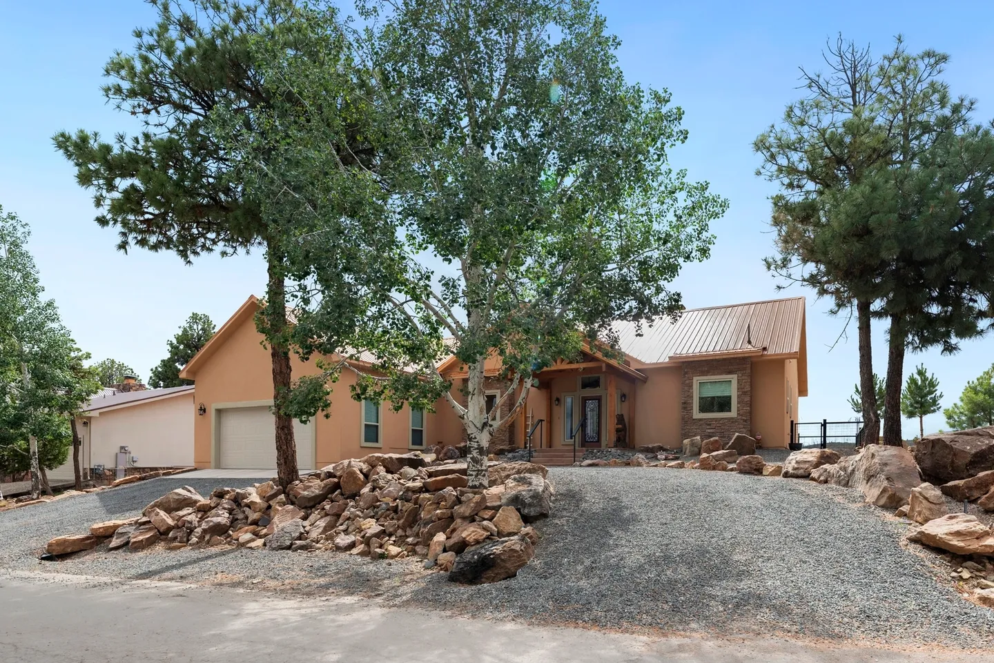Single-story house with a large tree and rock landscaping in front.