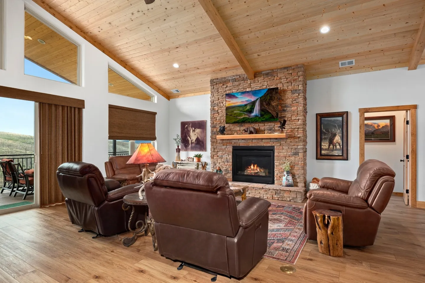 Cozy living room with leather sofas and a stone fireplace under a wooden ceiling.
