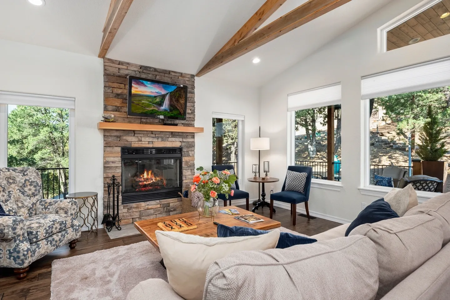 Cozy living room with stone fireplace and large windows.