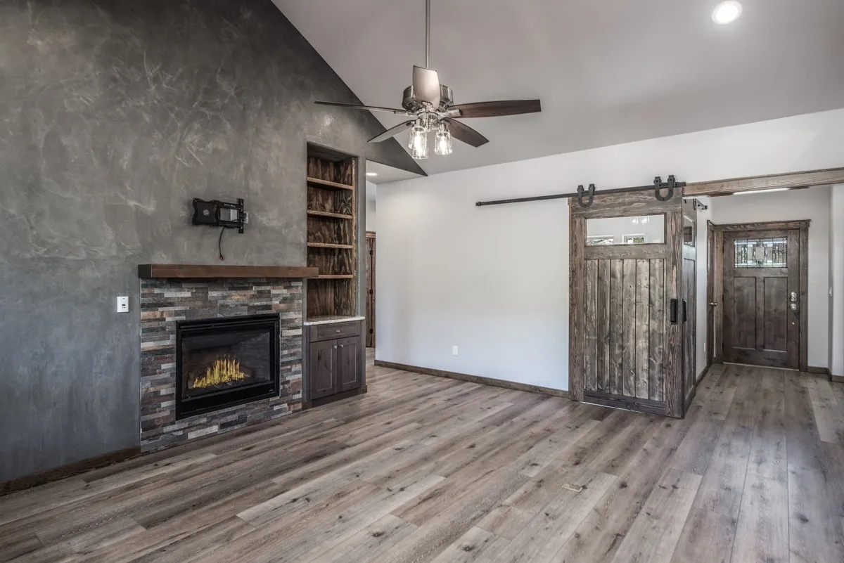 Modern rustic living room with barn door and fireplace.
