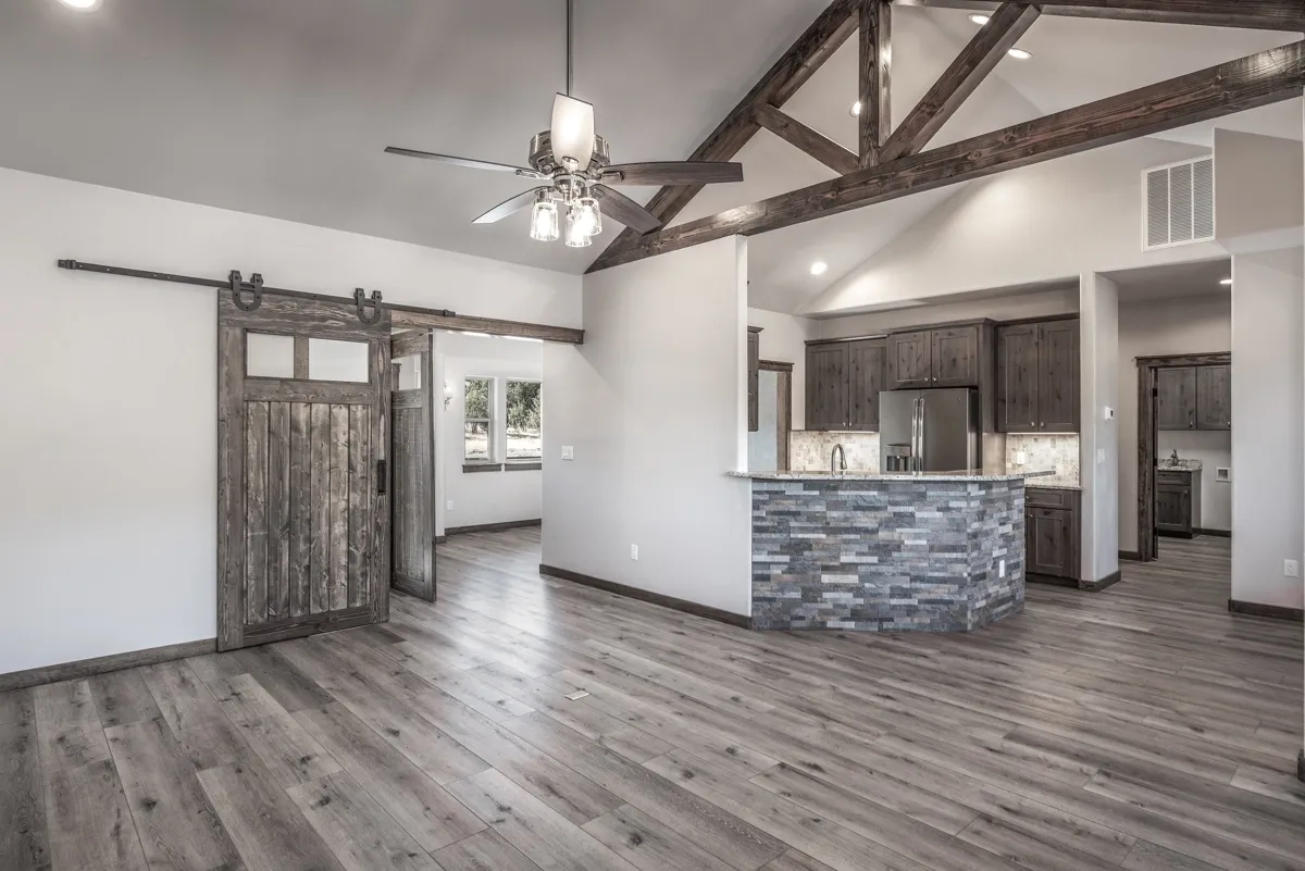 Modern open living space with rustic barn doors and exposed wooden beams.