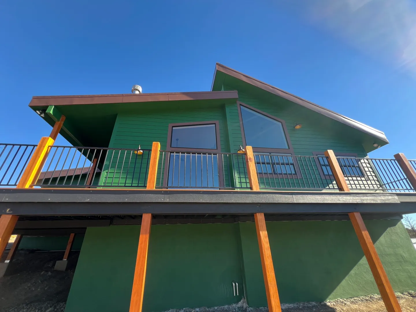 Green house with a balcony and clear blue sky.