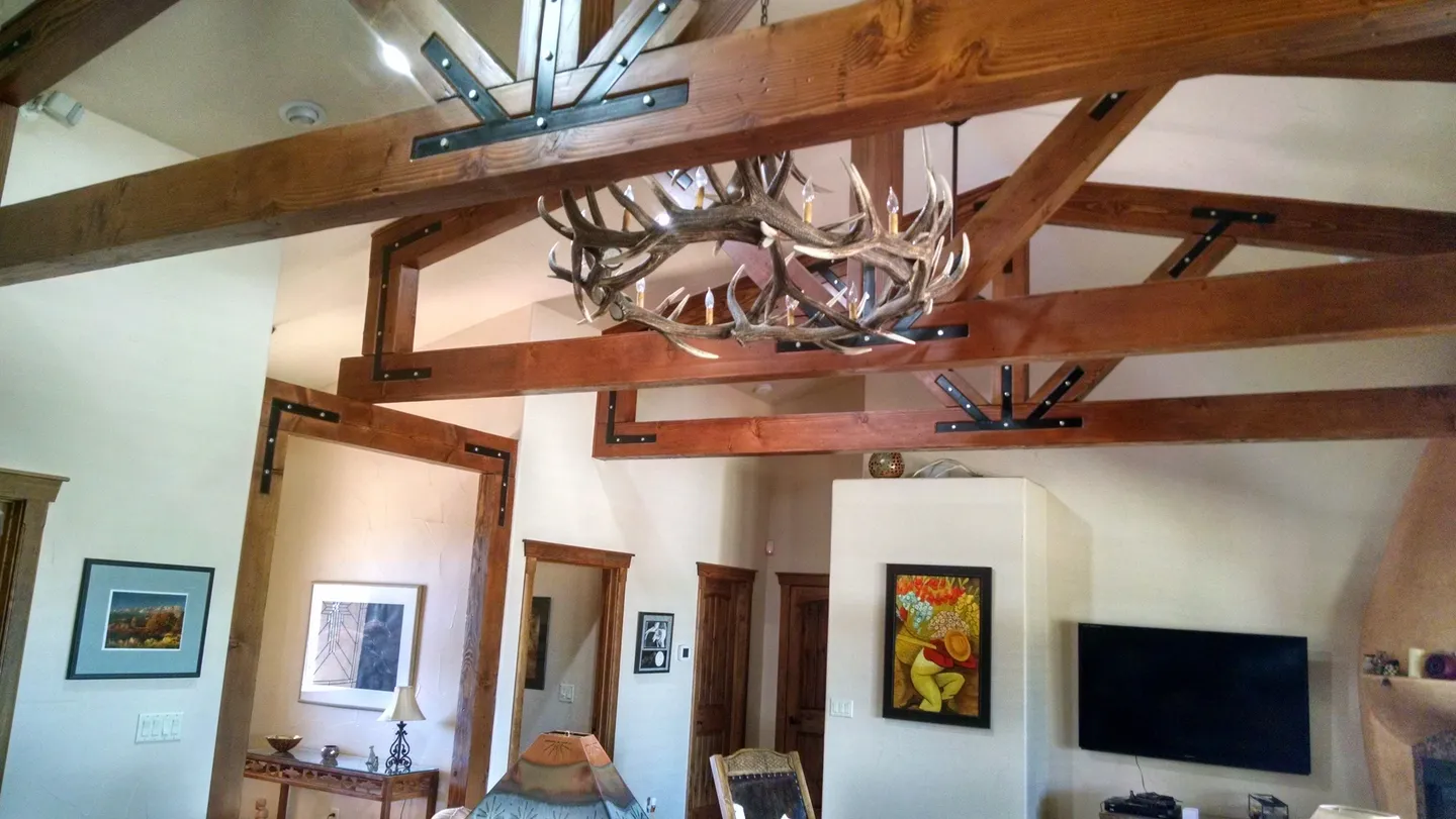 Rustic living room with wooden beams and antler chandelier.