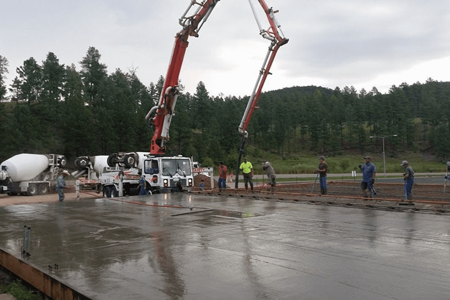 Concrete pouring with large mixer trucks and workers on site.