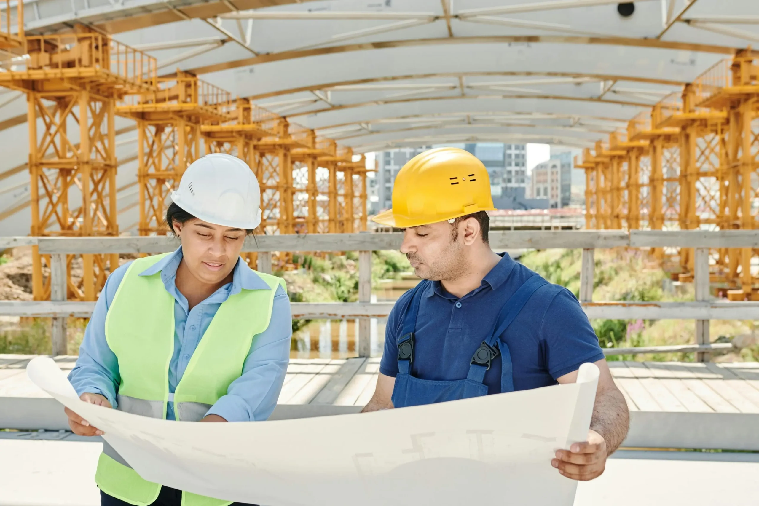 Two construction workers reviewing blueprints at a site.