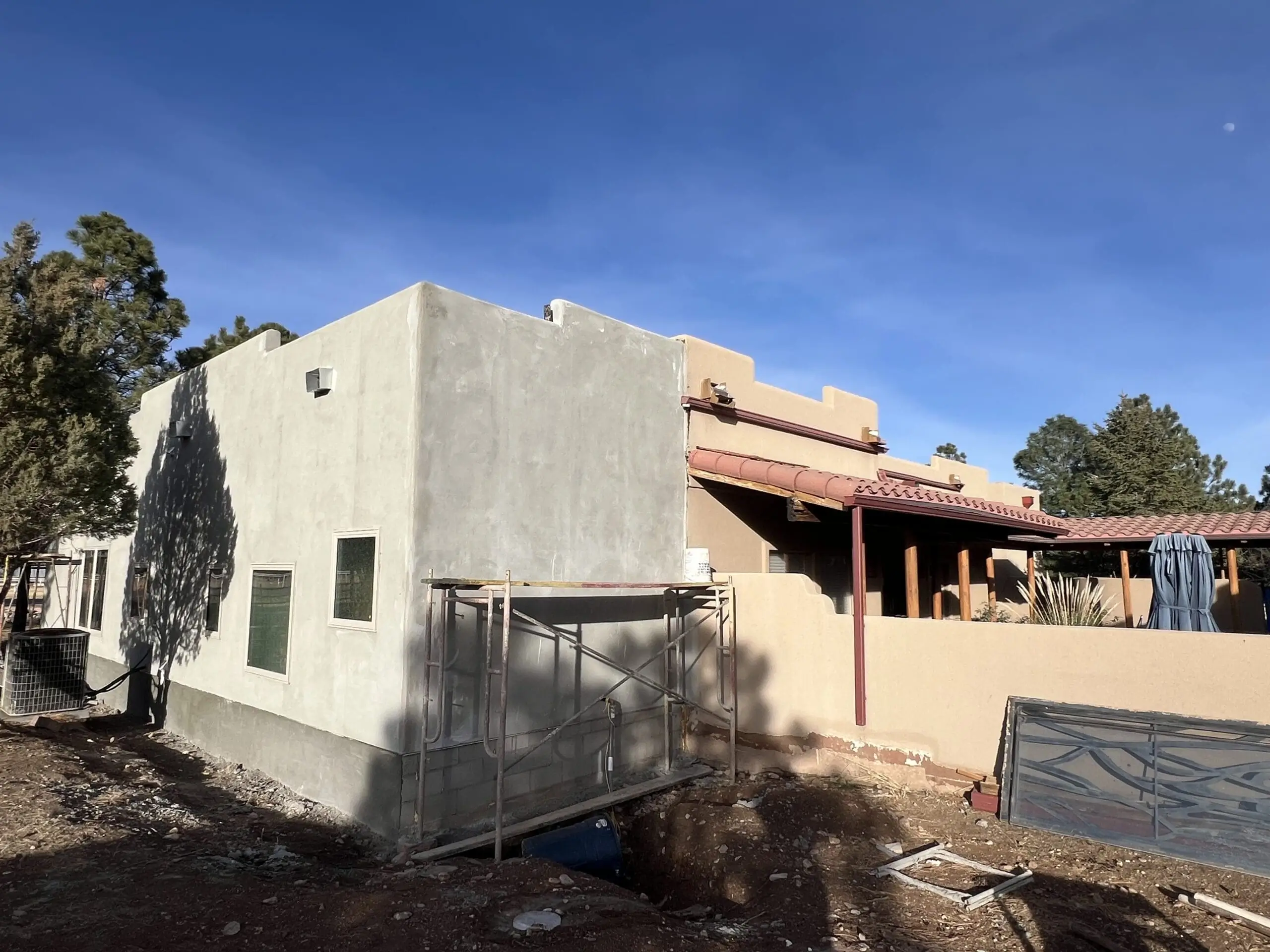 A partially constructed single-story house under a clear blue sky.